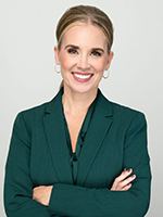 Woman in suit with arms crossed smiling at camera