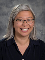 Woman with light hair and glasses smiling at camera