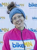 Woman with hair in bun, glasses, and biking jacket