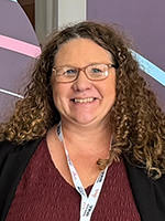 Woman with curly hair and glasses smiling