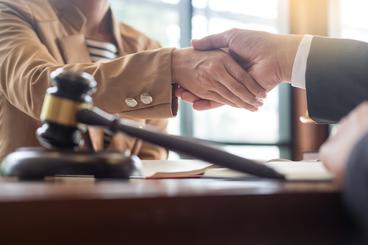 Lawyer shaking hands with client with gavel in foreground
